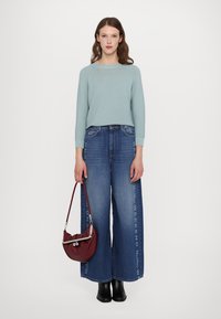 Pulover tricotat de culoare bleu deschis, cu mâneci lungi, asortat cu blugi largi cu imprimeu "WEEKEND", completat cu o geantă de umăr burgund.