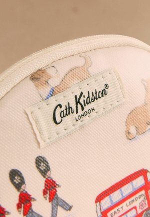 Stoffetikett mit der Aufschrift „Cath Kidston London“ auf einer beigen Tasche mit Illustrationen von Corgi-Hunden, britischen Wachen und einem roten Doppeldeckerbus.