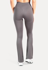 Grijze flare-legging gemaakt van rekbare stof, met een hoge tailleband en een gladde textuur. Onder de knie bevinden zich subtiele schijven.