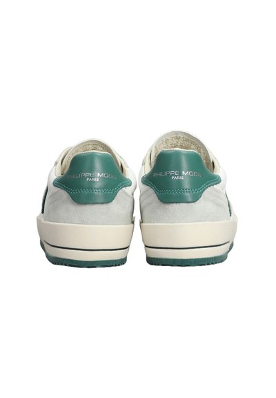Sneaker con un accento verde in pelle sul tallone, corpo in suede grigio e suola in gomma bianca con dettagli blu sottili e branding sul tallone.
