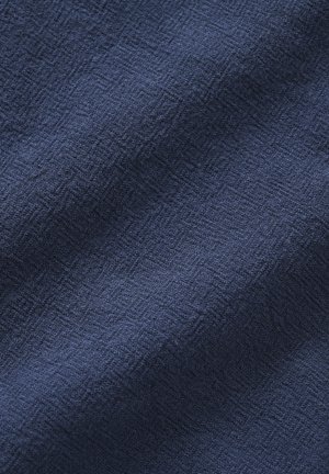 Tissu bleu foncé avec une texture discrète en losanges tissés, présentant de doux plis et de légères ombres sur la surface.