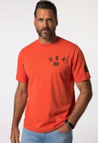 Oranžové bavlněné tričko s krátkými rukávy, na hrudi s černým potiskem "USA 80" a logem na rukávu. Volný střih.