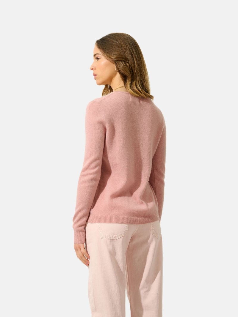 Roze wollen trui met een relaxte pasvorm, lange mouwen, geribde boorden en een ronde halslijn. Gepaard met lichtgekleurde broek.