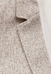 Tissu texturé beige clair avec un motif tissé, comportant des fils doux et légèrement en relief ainsi que des bords lisses. Convient pour les vêtements ou la décoration intérieure.