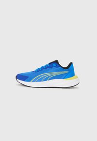 Baskets de sport bleues en matériau mesh, avec des accents noirs, une bande de logo jaune et une semelle blanche. Elles présentent un talon rembourré et un design à lacets.