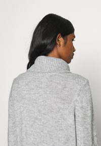 Γκρι πλεκτό πουλόβερ με υψηλό ribbed γιακά, απαλό υλικό και άνετη εφαρμογή. Διαθέτει λεπτό σχέδιο με μελανζέ υφή σε όλη την επιφάνεια.