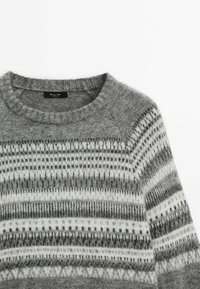 Pull en maille gris avec des motifs géométriques horizontaux blancs et gris foncé, et un col rond, sur un fond blanc.