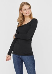 Zwarte lange mouwen top met een ronde hals, aansluitend ontwerp en zachte textuur, gecombineerd met blauwe slim-fit jeans.