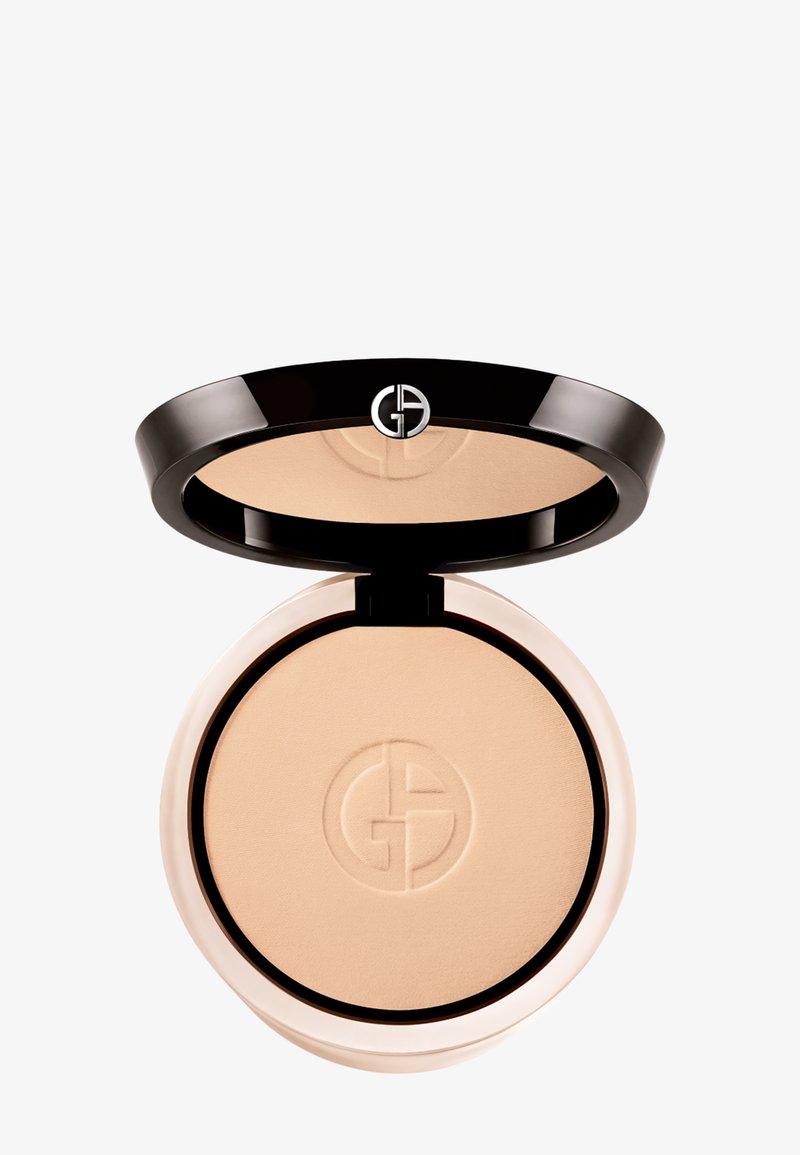 Trykt pudder kompakt med et svart, skinnende lokk, med en sølvfarget logo. Kremet beige puder inne med en jevn tekstur.