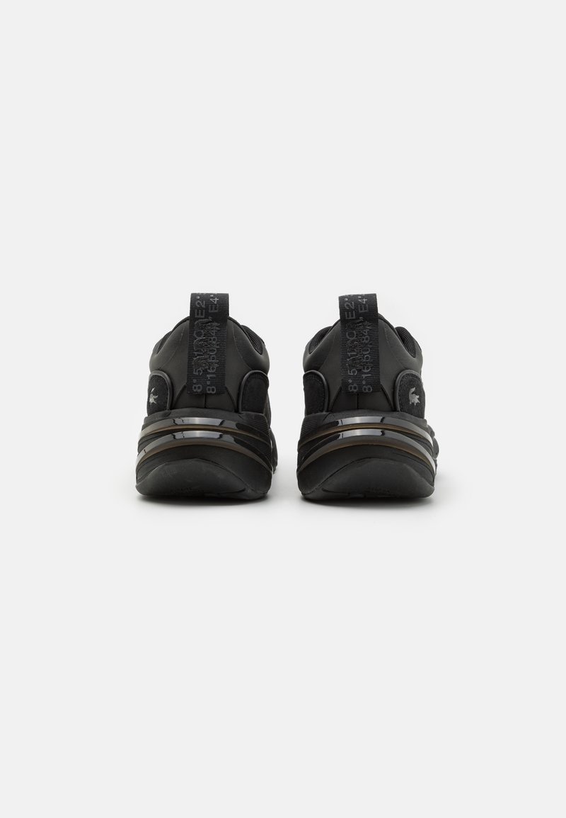 Czarne buty sportowe z gładką, fakturowaną cholewką, wyściełanym kołnierzem i wyraźną pętelką na pięcie. Posiadają warstwową podeszwę i elementy odblaskowe.