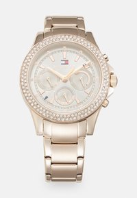 Montre en acier inoxydable doré avec une lunette ornée de cristaux, trois sous-cadrans et un cadran gris clair. Présente des accents et des maillons en or rose.