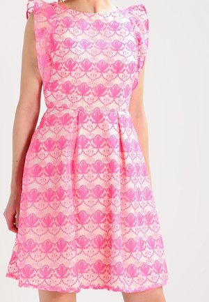 Ärmelloses pinkes Kleid mit floralem Spitzenmuster und gerafften Schulterdetails an einer Person vor hellem Hintergrund.