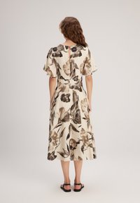 Blumenkleid in Beige mit kurzen, schwingenden Ärmeln, taillierter Passform, knielangem Saum und einem Schlüsselspalte-Detail im Rücken. Glattes, leichtes Material.