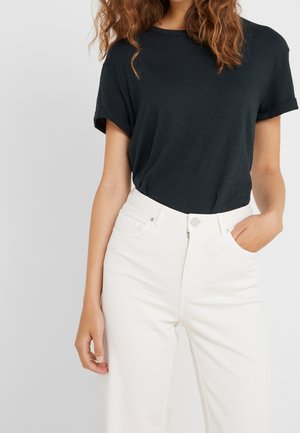 Czarny t-shirt z krótkim rękawem w połączeniu z białymi jeansami z wysokim stanem. T-shirt ma okrągły dekolt i miękką fakturę. Jeansy posiadają przednie kieszenie.