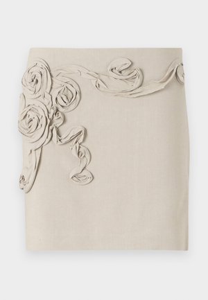 Beige linnen skjørt med teksturerte, stoffrosett-applikasjoner og snirklete bånddetaljer for et dimensjonalt utseende. Glatt overflate.