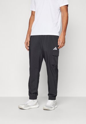 Black cargo pants with elastic cuffs, featuring a side pocket and white Adidas logo. Paired with a plain white short-sleeve shirt.