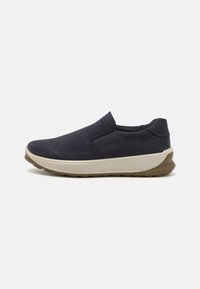 Slip-on sko i marineblå semsket skinn med en beige såle. Har et strømlinjeformet design, teksturert overdel og minimale søm detaljer.