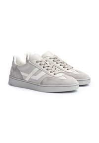 Een paar lichtgrijze sneakers van suède en leer met veters en een gestructureerde rubberen zool, iets schuin naar rechts geplaatst op een witte achtergrond.