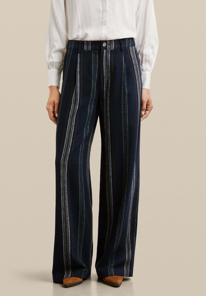 Pantalons larges en tissu bleu marine avec des rayures verticales en bleu clair, vert et marron. Comprend une fermeture à bouton et un design plissé.