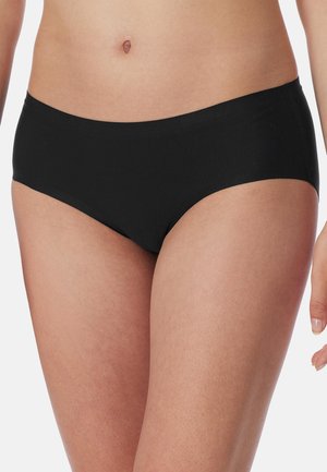 Nahaufnahme einer Person, die schwarze nahtlose Hipster-Unterwäsche trägt und den Oberkörper von der Taille bis zu den oberen Oberschenkeln zeigt.