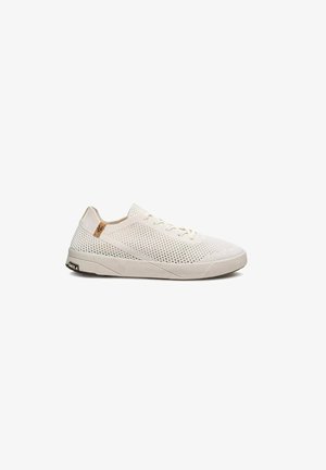 Lichtbeige lage sneaker met mesh bovenwerk, vetersluiting, platte rubberen zool en klein bruin logolabel dichtbij de hiel.