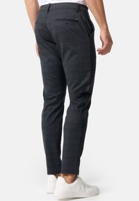 Pantalones de cuadros marinos, de corte slim, con un diseño elegante. Presenta bolsillos laterales y traseros, combinados con zapatillas blancas.