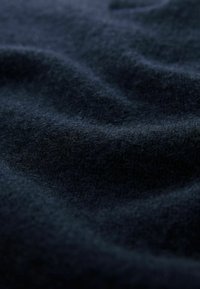 Tengerészkék gyapjú szövet puha, texturált felülettel, amely finom redők és diszkrét fényesség jellemzi, kiemelve gazdag mélységét és melegségét.