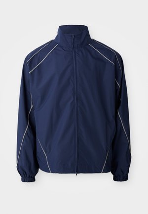 Veste coupe-vent marine, en matériau léger, fermeture éclair sur le devant, col montant, poignets élastiques et coutures d'accent gris le long des seams.