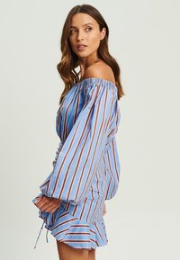 Off-Shoulder-Kleid aus blauer Baumwolle mit vertikalen braunen Streifen, ausgestattet mit langen Puffärmeln und einem ausgestellt geschnittenen Saum mit Rüschendetails.