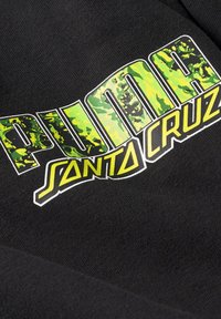 Sort stof med et iøjnefaldende grønt og sort mønsterlogo, hvor ordet "PUMA" er skrevet ovenover "SANTA CRUZ" i gult, med en glat overflade.