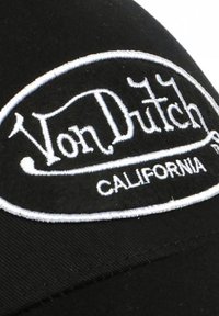 Casquette noire ornée d'un patch ovale brodé blanc avec "Von Dutch" et "CALIFORNIA" en lettrage stylisé. Texture de tissu lisse.