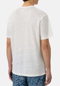 T-shirt bianco a maniche corte in un tessuto leggero e testurizzato. Design a girocollo con una vestibilità rilassata, visto da dietro.