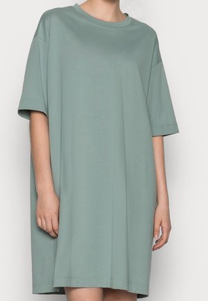 Oversized sukienka z krótkim rękawem w miękkim, stonowanym zielonym kolorze. Okrągły dekolt, luźny krój i prosty dół. Gładka, lekka tekstura.