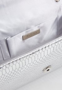 Silverhandväska med ett nätliknande yttre, metallisk lyster och slät satinfoder. Har en ficka och en märkesplåt i metall inuti.