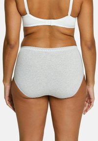 Una donna vista di spalle che indossa un reggiseno bianco e mutandine alte grigio chiaro su uno sfondo neutro.