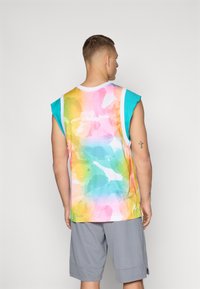 Ermeløs mesh tank topp med et flerfarget akvarellmønster i pastellfarger, med turkise tekstilinnslag ved skuldrene.