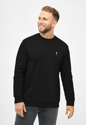 Black crewneck sweatshirt made of soft fabric with long sleeves, featuring a small white tree logo on the left chest and ribbed cuffs.