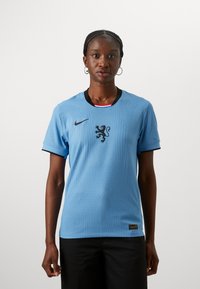Hele heleroheline spordimüts, ribidega tekstuur, must krae ja lõvikujutis keskel. Nike logo vasakus ülanurgas. Lühikesed varrukad.