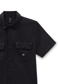 Camisa de botones de manga corta en negro, fabricada con tejido suave. Presenta dos bolsillos en el pecho y una etiqueta con el logotipo de Vans en el bolsillo izquierdo.