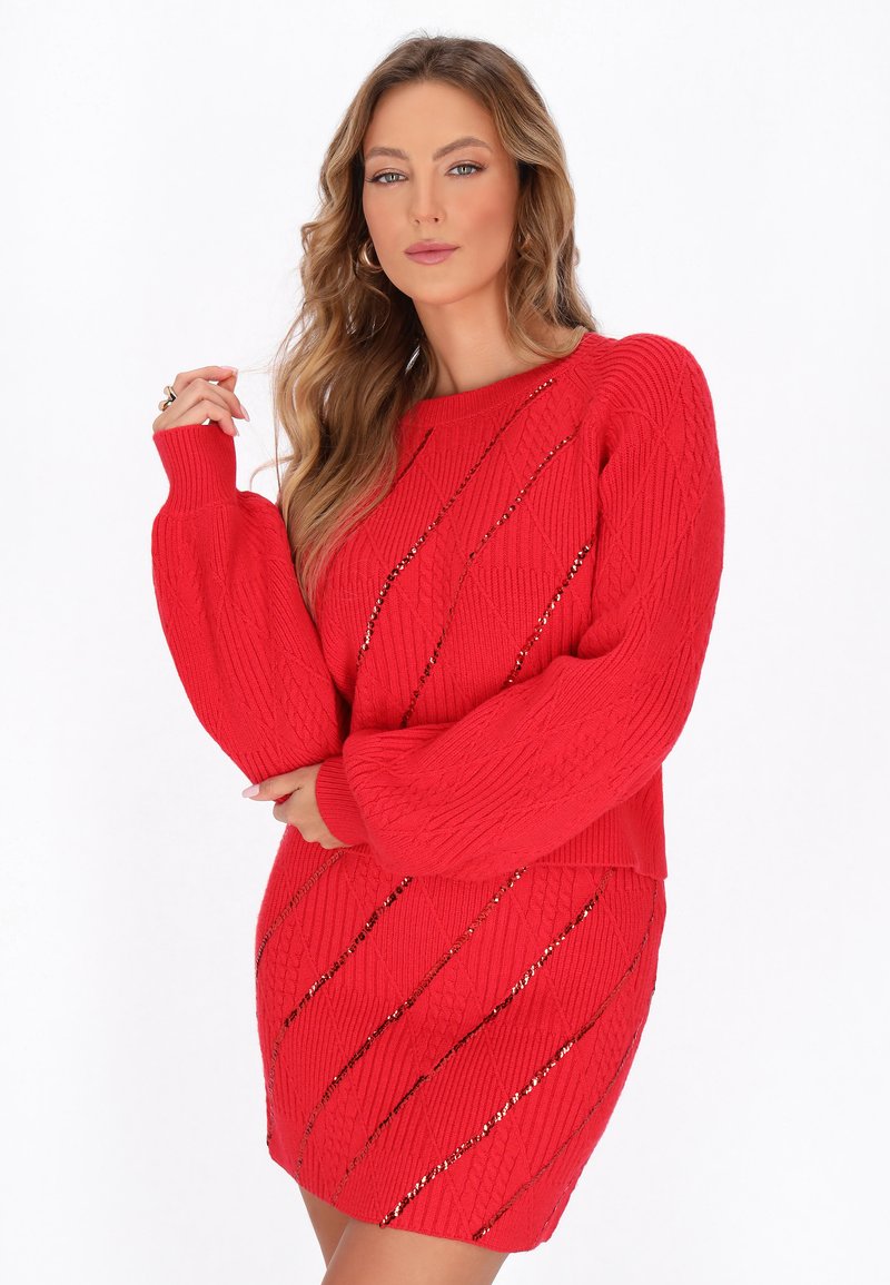 Rode gebreide trui jurk met volumineuze mouwen, voorzien van een diagonaal patroon en metallic accenten door de textuur geweven.