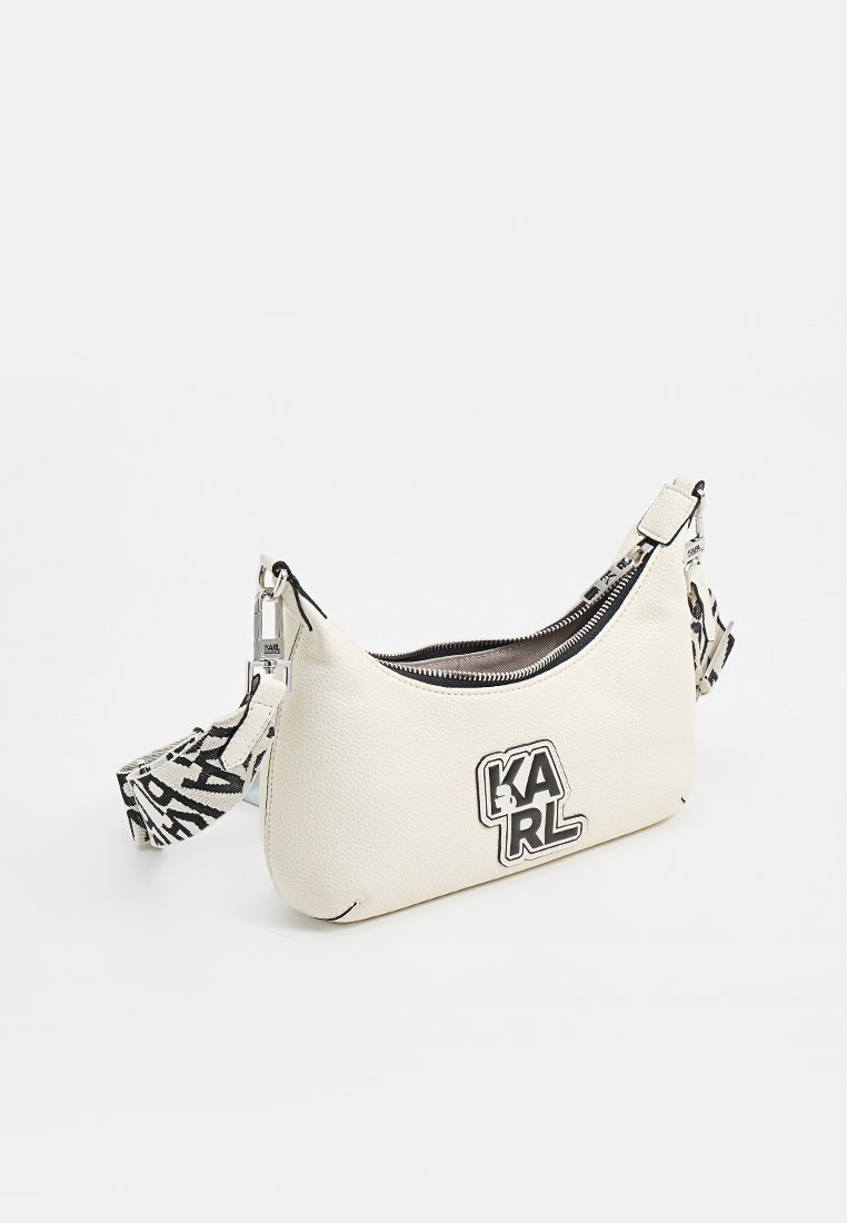 Sac à épaule en cuir blanc avec une forme courbée, doté d'une fermeture éclair noire, d'un détail de logo et d'une bandoulière à motifs pour un contraste supplémentaire.