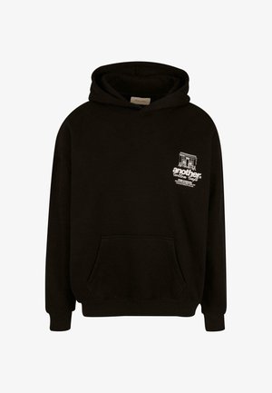 Fekete kapucnis pulóver elülső zsebbel, fehér nyomtatott szöveggel és grafikával a bal mellrészén. Puha pamutanyagból készült.