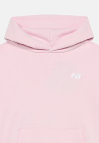 Hoodie rosa claro com bolso canguru e logo branco da New Balance no peito, mostrando detalhes da capuz e da parte frontal superior.