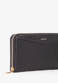 Portafoglio in pelle nera con pannello testurizzato, cerniera dorata e dettaglio con logo. Caratterizzato da un design elegante e rettangolare e superficie liscia.