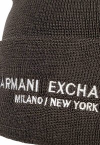 Dunkelgraue gestrickte Mütze mit geriffelter Textur. Mit weißer Stickerei mit dem Schriftzug "ARMANI EXCHANGE MILANO / NEW YORK".