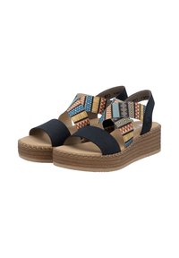 Black wedge sandals featuring a patterned fabric upper with geometric designs in blue, red, and yellow. Textured tan midsole and woven detailing.