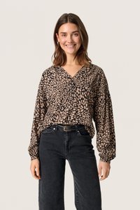 Mønstret, langærmet bluse i sort og tan med V-hals, knapdetaljer og flydende stof. Båret med højtaljede sorte jeans.