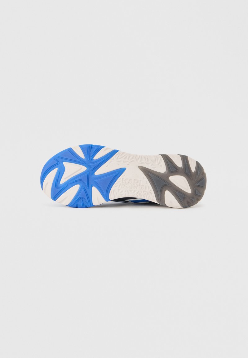 Suela de una zapatilla con dibujo de goma azul, blanco y gris que presenta patrones geométricos y texto de la marca grabado en el centro.