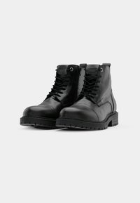 Botas de combate de cuero negro con suela gruesa, parte delantera con cordones y cremallera lateral. Presenta costuras resistentes y una textura suave.