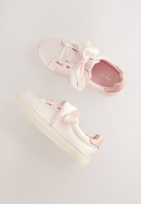 Hellrosa Sneaker aus Satinmaterial mit einer großen Schleife auf der Vorderseite und einer strukturierten Gummisohle. Die Ferse ist mit einem Akzent in Roségold versehen.